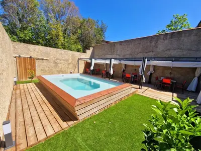 a backyard with a swimming pool and a patio with a deck at Appart Hôtel Du Grand Soleil in Saint-Chinian