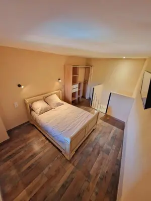 a bedroom with a bed and a wooden floor at Appart Hôtel Du Grand Soleil in Saint-Chinian