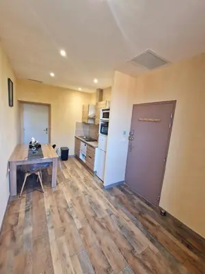 a kitchen with a wooden table and a wooden floor at Appart Hôtel Du Grand Soleil in Saint-Chinian