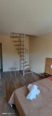 a room with a bed and a spiral staircase at Appart Hôtel Du Grand Soleil in Saint-Chinian