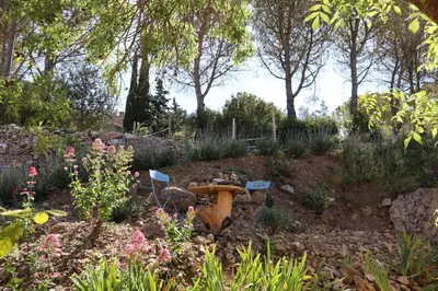 a garden with a table and some flowers and trees at MaCoCo Maison Coeur Corbieres in Fontjoncouse