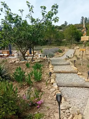 a stone path in a garden with parking meters at MaCoCo Maison Coeur Corbieres in Fontjoncouse