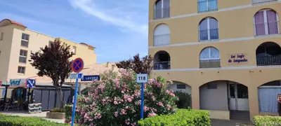 a large yellow building with flowers in front of it at Appartement T2 avec piscine, proche de la plage et du Port in Gruissan