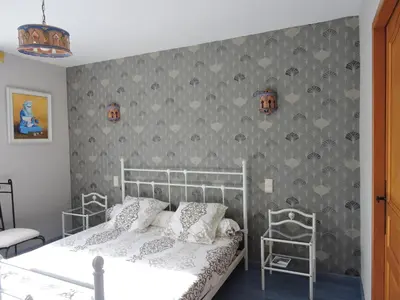 a bedroom with a white bed and a gray wall at Le Moulin du Barthas in Montredon-Labessonnié