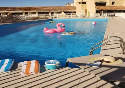 a swimming pool with a pink swan and people in it at Merveilleuse Port - Piscine - Plage - Climatisation - Commerces in Gruissan