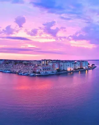 a town with a castle on a hill next to the water at Merveilleuse Port - Piscine - Plage - Climatisation - Commerces in Gruissan