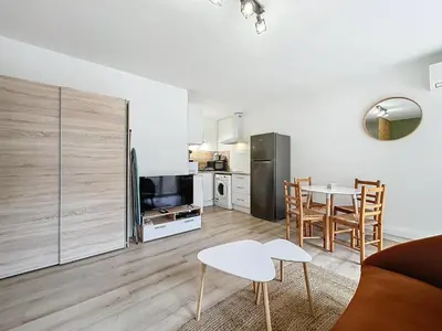 a living room with a table and a kitchen at Studio Cosy - Balcon - Wifi - Free parking in Narbonne