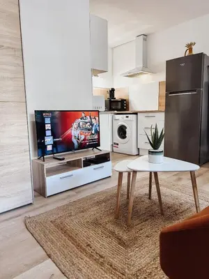 a living room with a table and a tv in it at Studio Cosy - Balcon - Wifi - Free parking in Narbonne