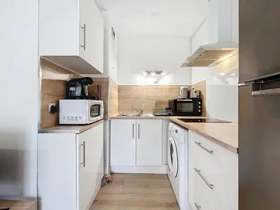 a small white kitchen with white cabinets and appliances at Studio Cosy - Balcon - Wifi - Free parking in Narbonne