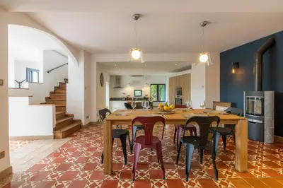 a kitchen and living room with a wooden table and chairs at Sous les remparts la maison Pimprenelle in Carcassonne