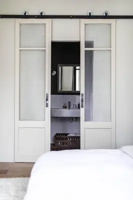 a bedroom with white doors and a mirror at Camellas-Lloret in Montréal