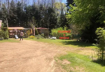 a man standing on a dirt road with a donate a drug sign at La Cabane in Mazamet