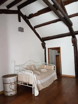 a bedroom with a white bed and a wooden floor at Le Gîte Dame Nature in La Tourette-Cabardès