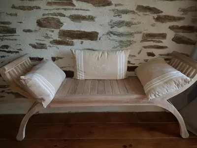 a wooden bench with two pillows on it at Le Gîte Dame Nature in La Tourette-Cabardès