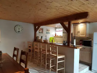 a kitchen with a counter and chairs and a clock at Le Gîte Dame Nature in La Tourette-Cabardès