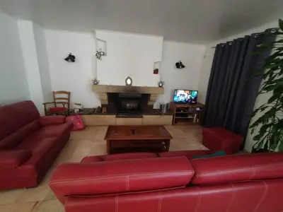 a living room with a red couch and a fireplace at La Maison de Raph in Villeneuve dʼOlmes