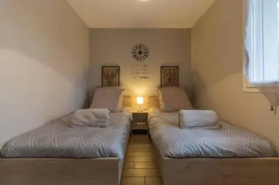 two beds in a room with a light on the wall at Gîte à la Ferme de la Bouriette in Revel