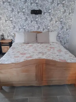 a bedroom with a wooden bed with a floral wallpaper at L'atelier des rêves in Capestang
