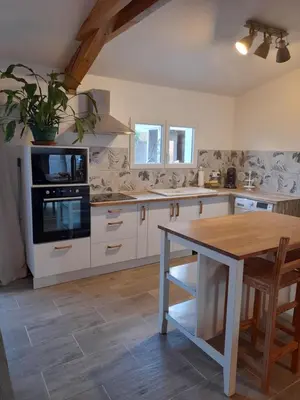 a kitchen with white cabinets and a wooden table at L'atelier des rêves in Capestang