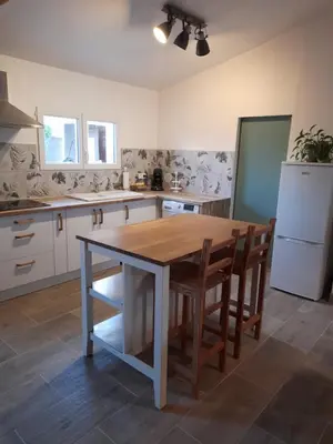a kitchen with a wooden table and chairs at L'atelier des rêves in Capestang