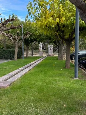 a park with trees and a statue in the grass at L'Incarnat in Caunes-Minervois