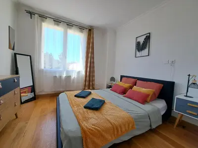 a bedroom with a large bed with red and yellow pillows at Appartement Bora Bora in Narbonne