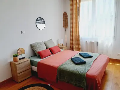 a bedroom with a bed with red and green sheets at Appartement Bora Bora in Narbonne