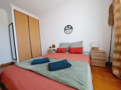 a bedroom with a large bed with red and blue pillows at Appartement Bora Bora in Narbonne