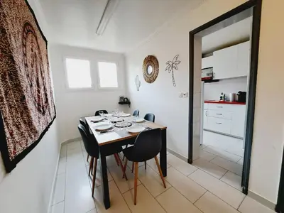a dining room table with black chairs and a kitchen at Appartement Bora Bora in Narbonne