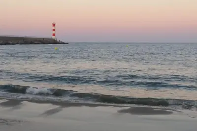 a red lighthouse in the ocean next to the beach at Appartement spacieux avec grand patio, 1er étage in Sigean