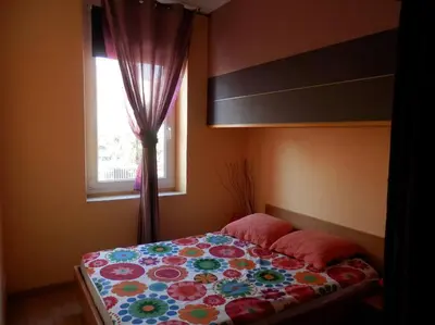 a bedroom with a bed with a floral bedspread and a window at Appartement spacieux avec grand patio, 1er étage in Sigean