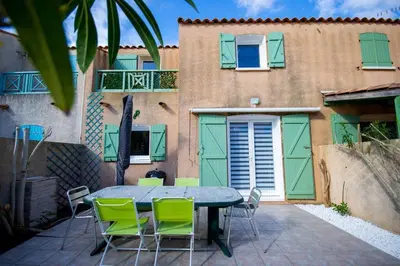 a patio with a table and chairs in front of a building at La Maisonnette YourHostHelper in Gruissan