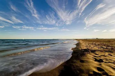 a beach with the ocean and a cloudy sky at La Maisonnette YourHostHelper in Gruissan