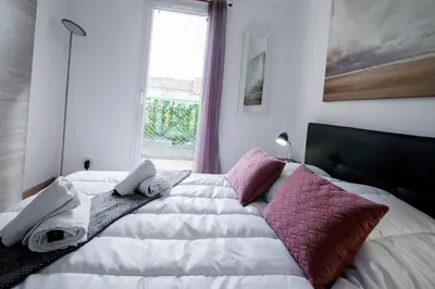 a bedroom with a large white bed with pink pillows at La Maisonnette YourHostHelper in Gruissan