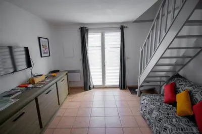 a living room with a staircase and a room with a couch at La Maisonnette YourHostHelper in Gruissan