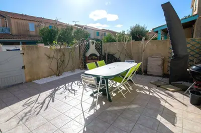 a patio with a table and chairs and a fence at La Maisonnette YourHostHelper in Gruissan
