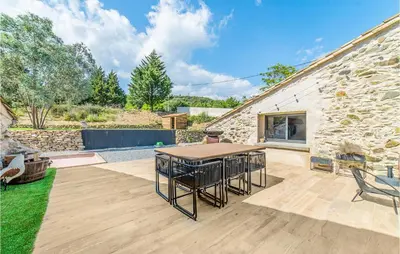 a patio with a table and chairs and a stone building at Stunning Home In Pardailhan in Pardailhan