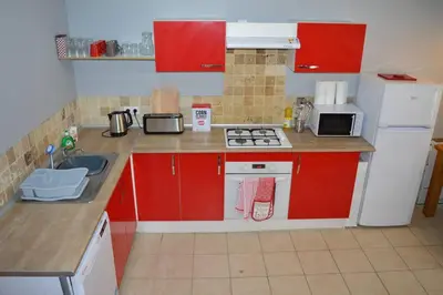 a small kitchen with red cabinets and a white refrigerator at Spacious stone village house in Puivert in Puivert
