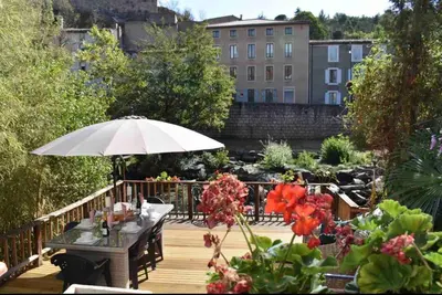a wooden deck with a table and an umbrella at Riverside 4 bed house full of character and charm in Quillan