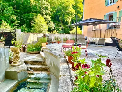 a garden with a pond and some plants and an umbrella at Notre-Dame d'Escouloubre Sources d'eaux chaudes privées et sauna in Escouloubre