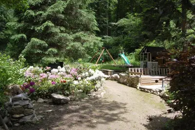 a garden with a playground and flowers and a bench at Notre-Dame d'Escouloubre Sources d'eaux chaudes privées et sauna in Escouloubre