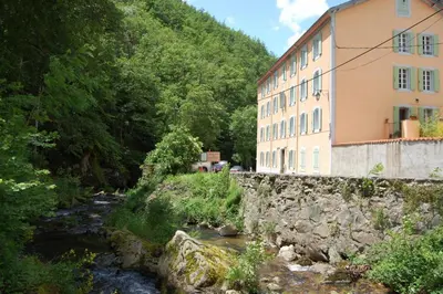 a building next to a river next to a mountain at Notre-Dame d'Escouloubre Sources d'eaux chaudes privées et sauna in Escouloubre