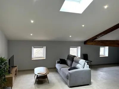 a living room with a couch and a table at Le Cosy Grenier de Pauline et Flo in Cessenon