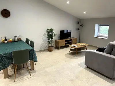 a living room with a table and a couch and a television at Le Cosy Grenier de Pauline et Flo in Cessenon