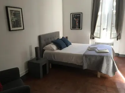 a bedroom with a bed with blue pillows and a chair at Le Voyageur - Chambres d'Hôtes in Olonzac