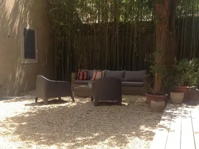 a patio with a couch and chairs in a yard at Le Voyageur - Chambres d'Hôtes in Olonzac