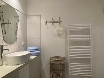 a white bathroom with a sink and a mirror at Gîte de 12 personnes au cœur d'un domaine viticole in Gruissan