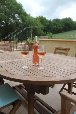 a wooden table with two glasses and a bottle of wine at Gîte - La Couderquié in Lautrec