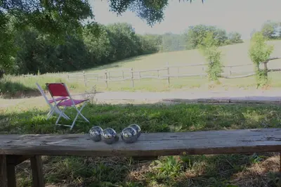 a wooden table with a chair and a bench with a chair and a chair at Gîte - La Couderquié in Lautrec