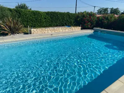 a swimming pool with blue water in a yard at Tiny-house chez l'habitant in Lautrec